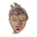 Helmmaske mit geschnitzten AugenlidernDR Kongo, Holz, rotbraun, weiß und schwarz gefärbt, Bastbehang