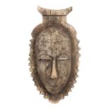 Maske der GuroElfenbeinküste, Holz mit grauer Patina, mit Bekrönung und gezackter Kontur, H: 33 cm.-