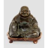 A SITTING BUDDHA China Patinated bronze. Wooden base. 12 cm highSITZENDER BUDDHAChina Patinierte