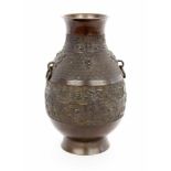 A VASE Japan Bronze with a surrounding relief decoration and side rings as handles. 25.5cm high.