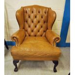 A Georgian style tan leather Wing Back Armchair, buttoned upholstery to the back, scroll arms,