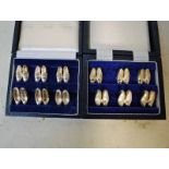Two cased sets of six pairs of silver Place Card Holders modelled as miniature pairs of Ladies and