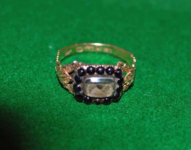 A George III 18ct gold Mourning Ring set with a hair locket surrounded by small black glass beads,