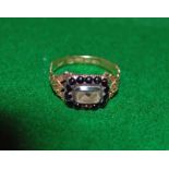 A George III 18ct gold Mourning Ring set with a hair locket surrounded by small black glass beads,
