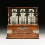 AN ENGLISH GOTHIC REVIVAL BRONZE MOUNTED OAK TANTALUS AND CUT GLASS DECANTERS SET, CIRCA 1900, in