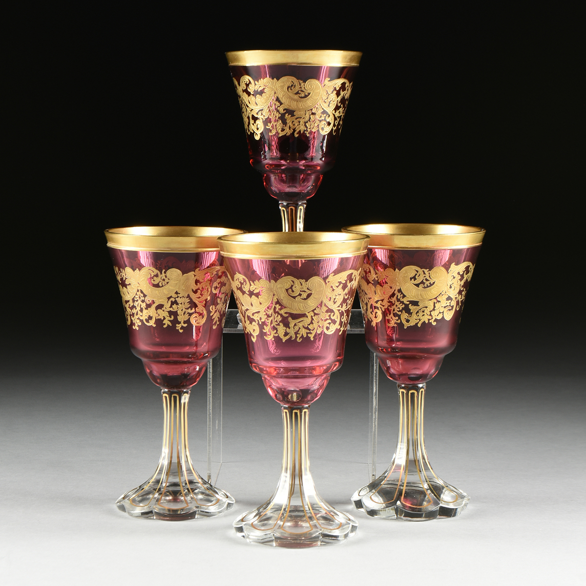 A SET OF FOUR BACCARAT STYLE GILT OVERLAY CRANBERRY TO CLEAR GOBLETS, CIRCA 1900, the gilt rims over