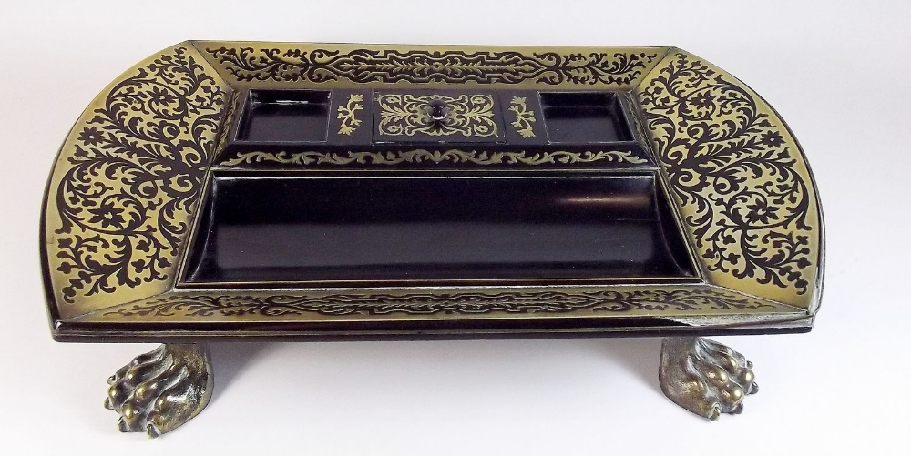 A Regency ebony desk stand with inkwells and pen tray, within deep brass floral borders, all
