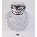 A large cut glass inkwell with silver top embossed Art Nouveau flowers