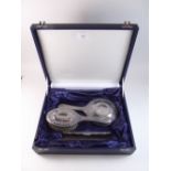 A silver three piece dressing table and brush set with embossed decoration Sheffield 2001, cased