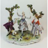 An early 20th century Dresden porcelain group of a woman on a swing flanked by two others. 22cm