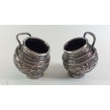 A pair of Indian Kashmiri silver plated embossed handled salt pots