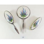 A three piece white metal and enamel dressing table set with foxglove decoration