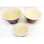 Two large cream glazed pottery dough bowls and a smaller one