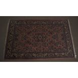 A Middle-Eastern woollen rug, floral and scroll decoration on terracotta ground,