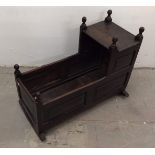 A 17th Century oak cradle, rectangular body and hood on two curved rockers, six finials, 93 cm