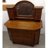 An early 20th Century Arts and Crafts oak dressing table, arched bevelled framed mirror flanked by