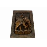 A 20th Century Indian carved wooden relief sculpture of three figures riding on an elephant, in a