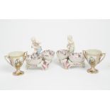 A pair of Dresden porcelain figural double salts, each with putto above baskets, blue crossed