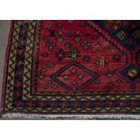 A Kazak woollen rug, central indigo pole medallion on red ground, indigo and ivory border,