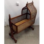 A Victorian oak and cane panelled cot, ogee hood with finials, raised on turned supports, 89 cm long