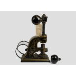 A late 19th/early 20th Century painted metal stamping machine, gilt scroll decoration on black