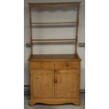 A 19th Century waxed pine dresser, plate rack with shaped pediment above two short drawers, two