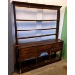 An antique oak dresser, five short drawers, arched apron above pot board, with separate open plate