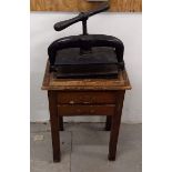 A 19th Century cast iron book press raised on mahogany stand, two frieze drawers, 56 cm wide x 38 cm