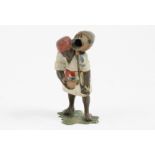 A die cast figure of an African man, carrying a water vessel on his shoulder with a cup in his other