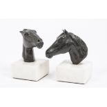 A pair of 20th Century decorative book ends, featuring bronze horse heads upon square white marble