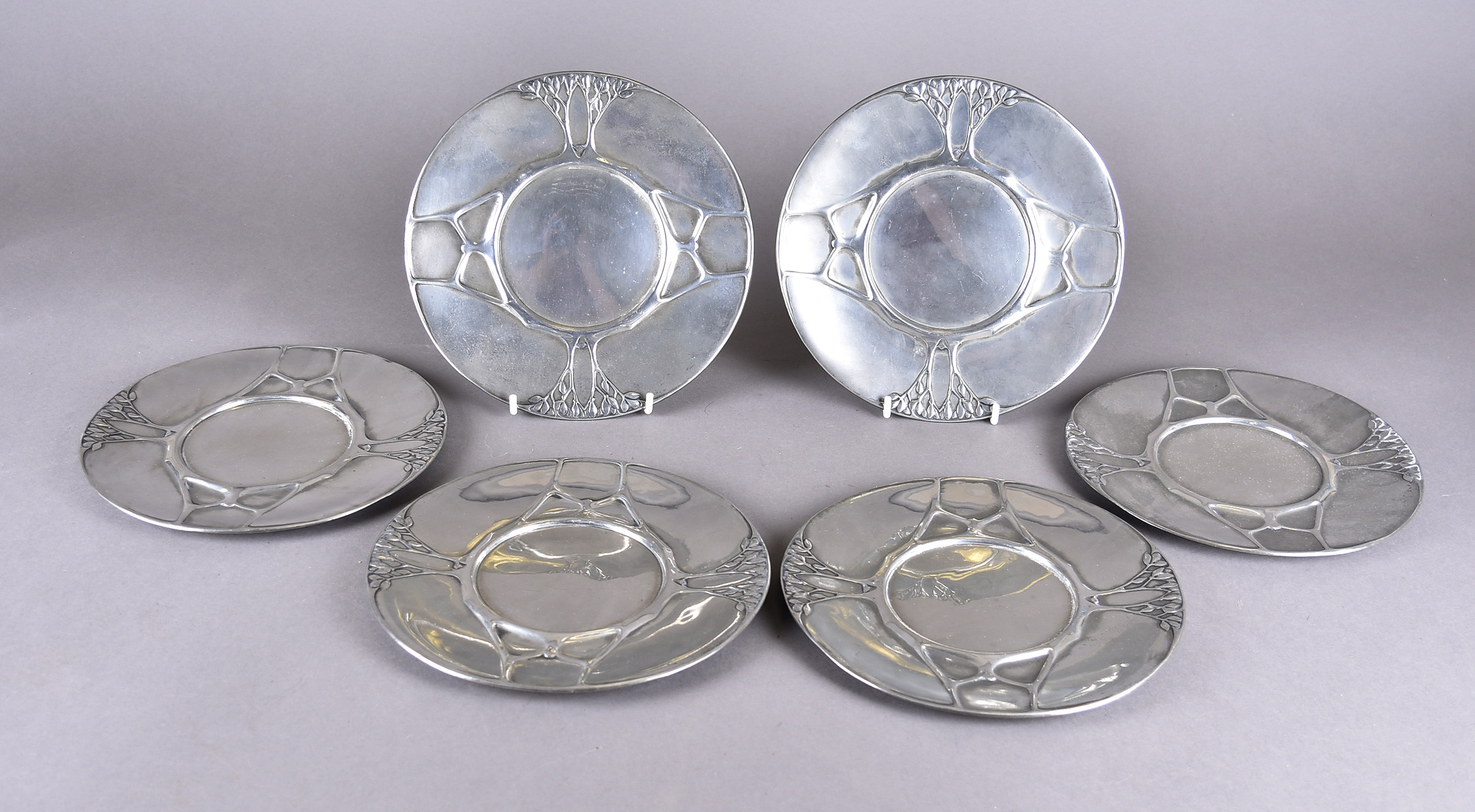 A set of six pewter Urania Art Nouveau plates, decorated with sinuous trees and stylised leaves,