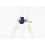 A modern 18ct gold sapphire and diamond three stone ring, central rectangular cut blue sapphire