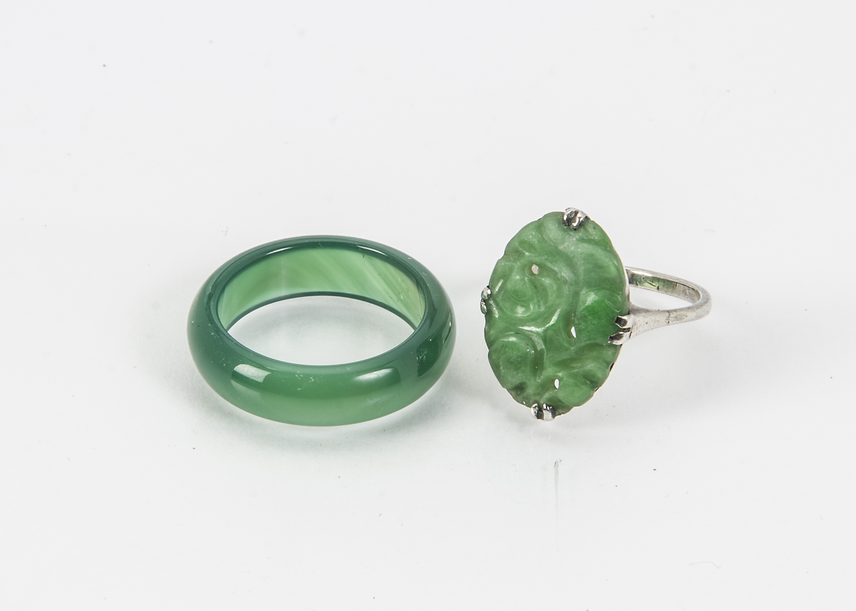 A vintage Chinese jade and white metal ring, together with a green hardstone band ring (2)