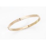 A 1970s Middle Eastern gold bangle, hinged with single line to centre, marked 14k, 22.2g