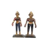 Two plastered wooden figures, painted in traditional clothing and standing upon plinths, 32 cm