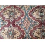 A 20th Century Middle Eastern woollen carpet, with six geometric medallions upon a purple ground and