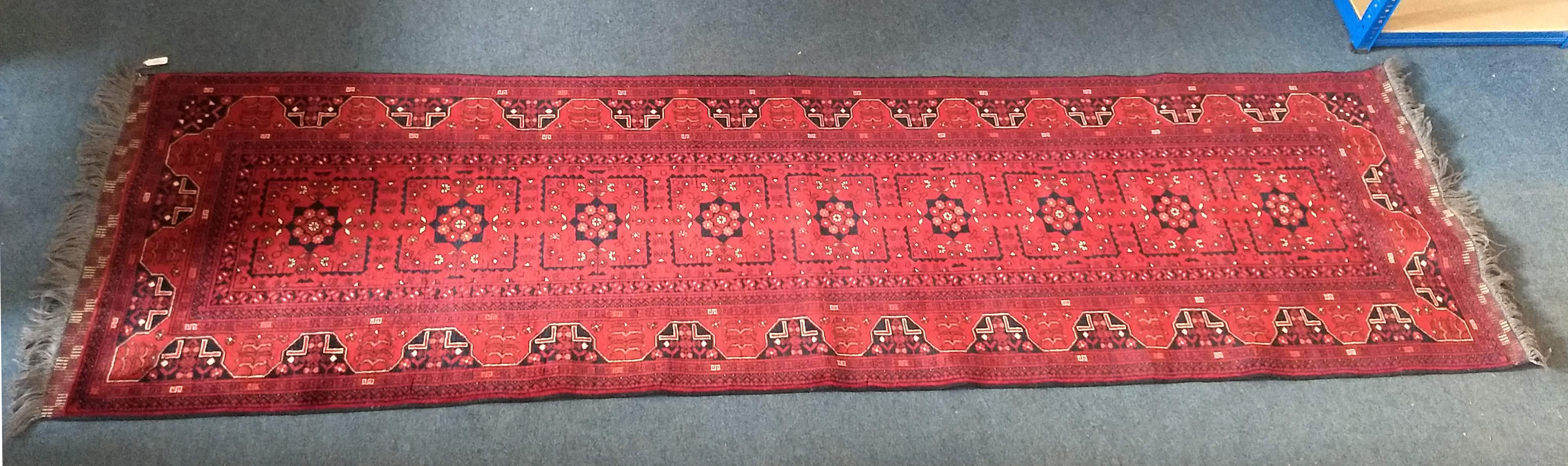 A Turkoman runner, the red ground with a row of nine shaped medallions surrounded by stylized flower