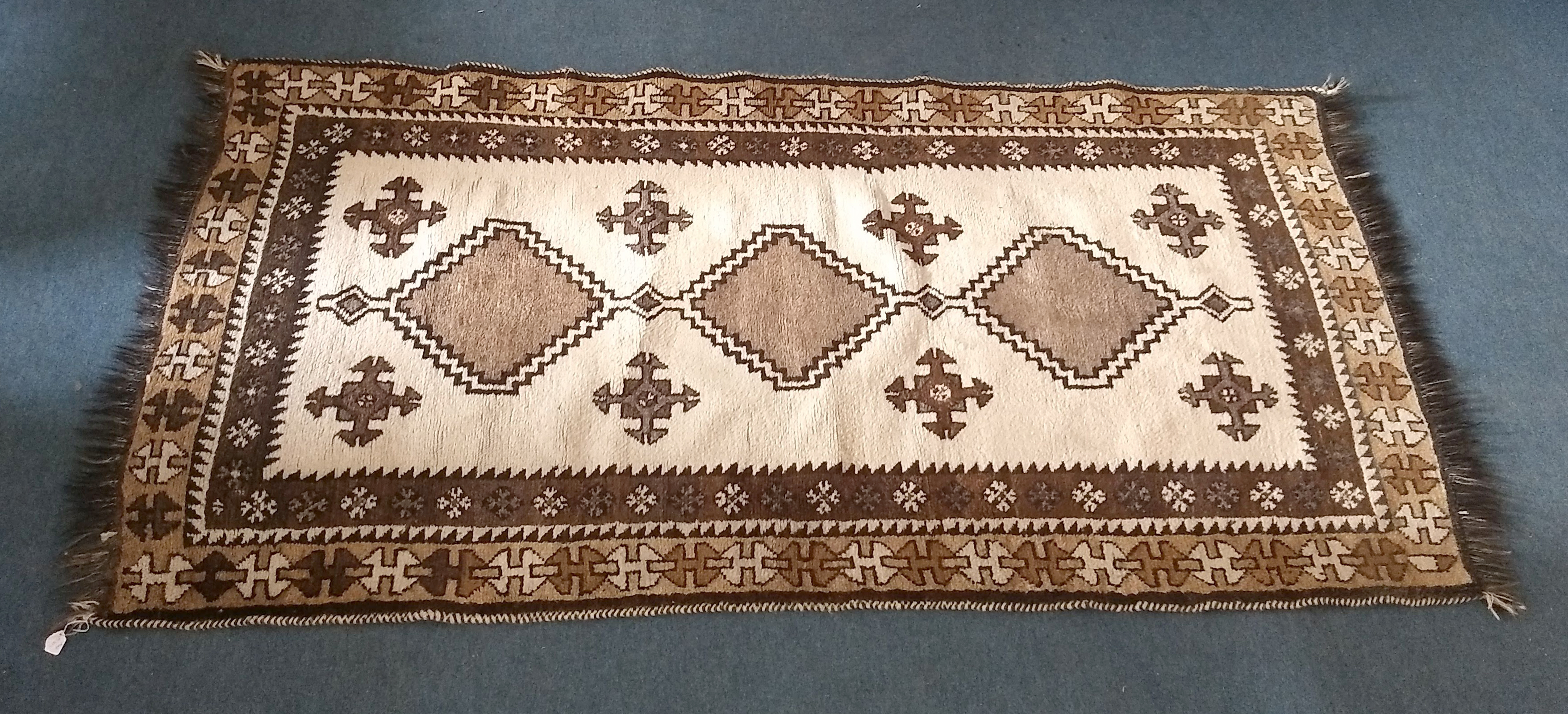 A mid 20th Century Kurdish rug, cream field with three large brown central hooked medallions and