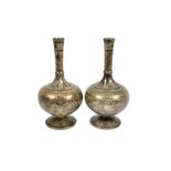 A pair of brass bottle vases, the exteriors inlaid with assorted metals and depicting temples and