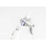 A contemporary tanzanite and diamond dress ring, the step cut tanzanite in four claw setting flanked