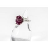 A contemporary carved ruby and diamond 18ct white gold dress ring, the oval carved ruby of floral