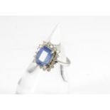 A sapphire and diamond cluster ring, the rectangular mixed cut pale blue sapphire in four claw