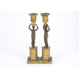 A pair of gilt bronze and brass figural candlesticks, modelled as women dressed in classical attire,