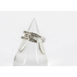 An 18ct gold diamond crossover dress ring, in white metal with three brilliant cuts in tension