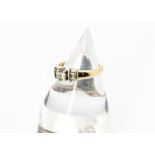 A 14ct gold princess cut diamond dress ring, the central stone in four claw setting flanked by