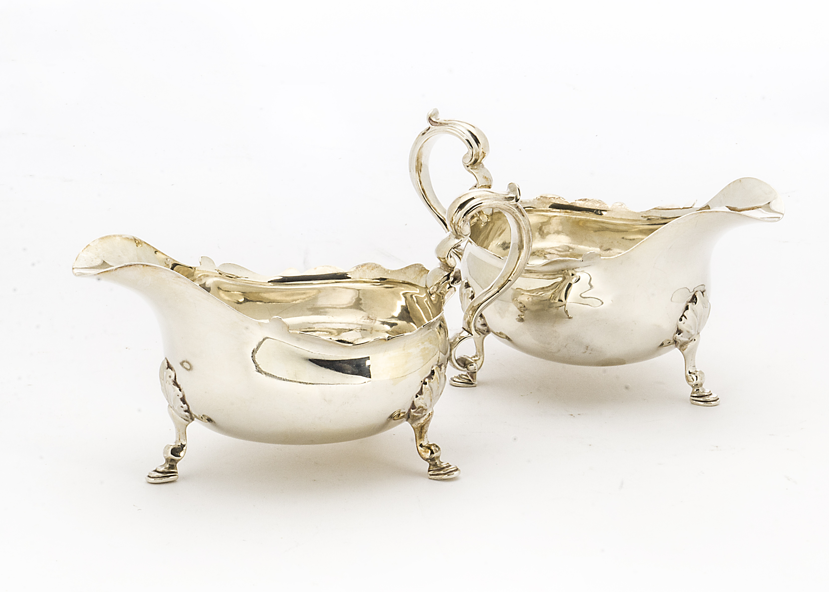 A pair of Edwardian silver sauce boats by Thomas Bradbury & Sons, pie crust rims on three hoof