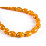 A uniform string of imitation amber beads, on a modern snap clasp, each oval bead measuring 19mm,