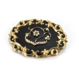 A 19th Century yellow metal mourning brooch, with black enamel front piece mounted with seed