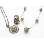 A collection of Ethiopian filigree white metal jewellery, including a roundel medallion, a sphere