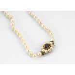 A string of graduated cultured, knotted pearls, matinee length, with a 9ct gold garnet and pearl